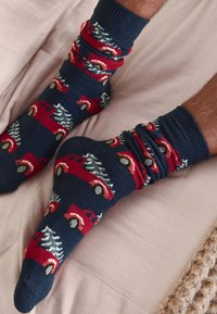 Põlvikuni ulatuvad tumesinised sokid punase auto ja jõulupuu mustriga. Pehme tekstuur, soonilised ääred ja ümar varbaga disain.