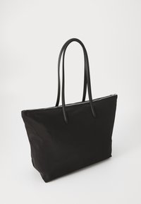 Black nylon tote bag with two long, flat handles, a top zip closure, and a structured shape. Smooth texture with no visible patterns.