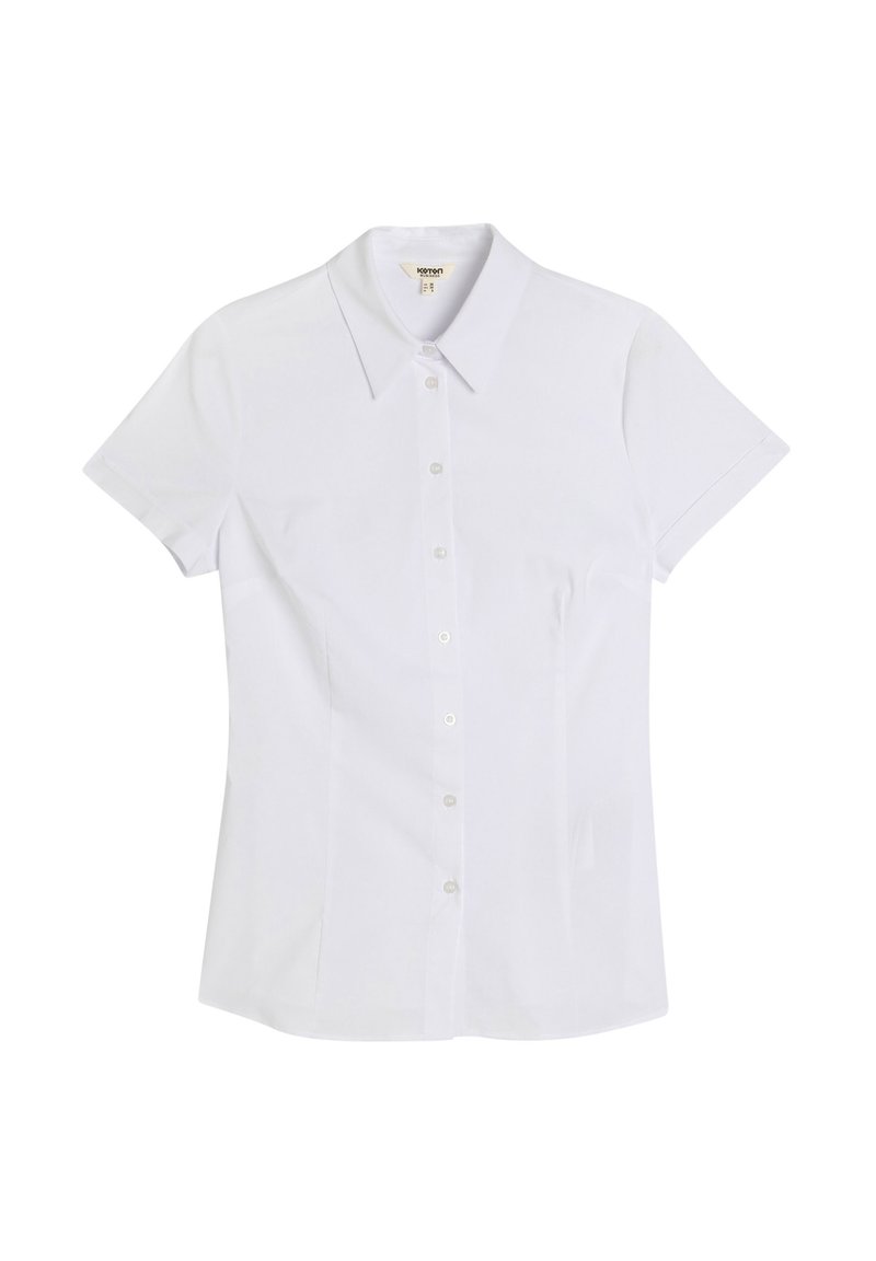 Camicia bianca a maniche corte con colletto rigido, realizzata in tessuto liscio. Presenta una forma aderente e sei bottoni trasparenti lungo il davanti.