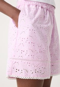 Rosa broderte shortser med et teksturert mønster, elastisk midje og blondekantdetaljer ved kanten og lommene.
