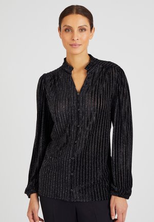 Blusa de terciopelo negro con cuello alto, mangas largas y rayas plateadas verticales. Con cierre de botones en el frente.