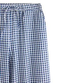 Niebieskie i białe spodnie w wzór w kratkę z elastycznym pasem i związanym sznurkiem z przodu.