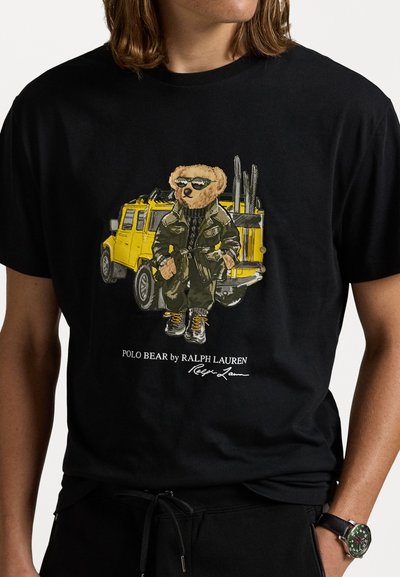 Tricou din bumbac negru, cu un grafism reprezentând un urs îmbrăcat într-o ținută verde, purtând ochelari de soare, stând în fața unei mașini galbene.