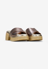 Sandalias de slide metálicas en bronce con tiras cruzadas anchas, plantilla acolchada y suela texturizada estilo yute. Diseño de tacón plano.