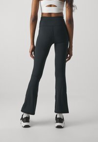 Under Armour MOTION FLARE PANT - Legingi - black/jet gray