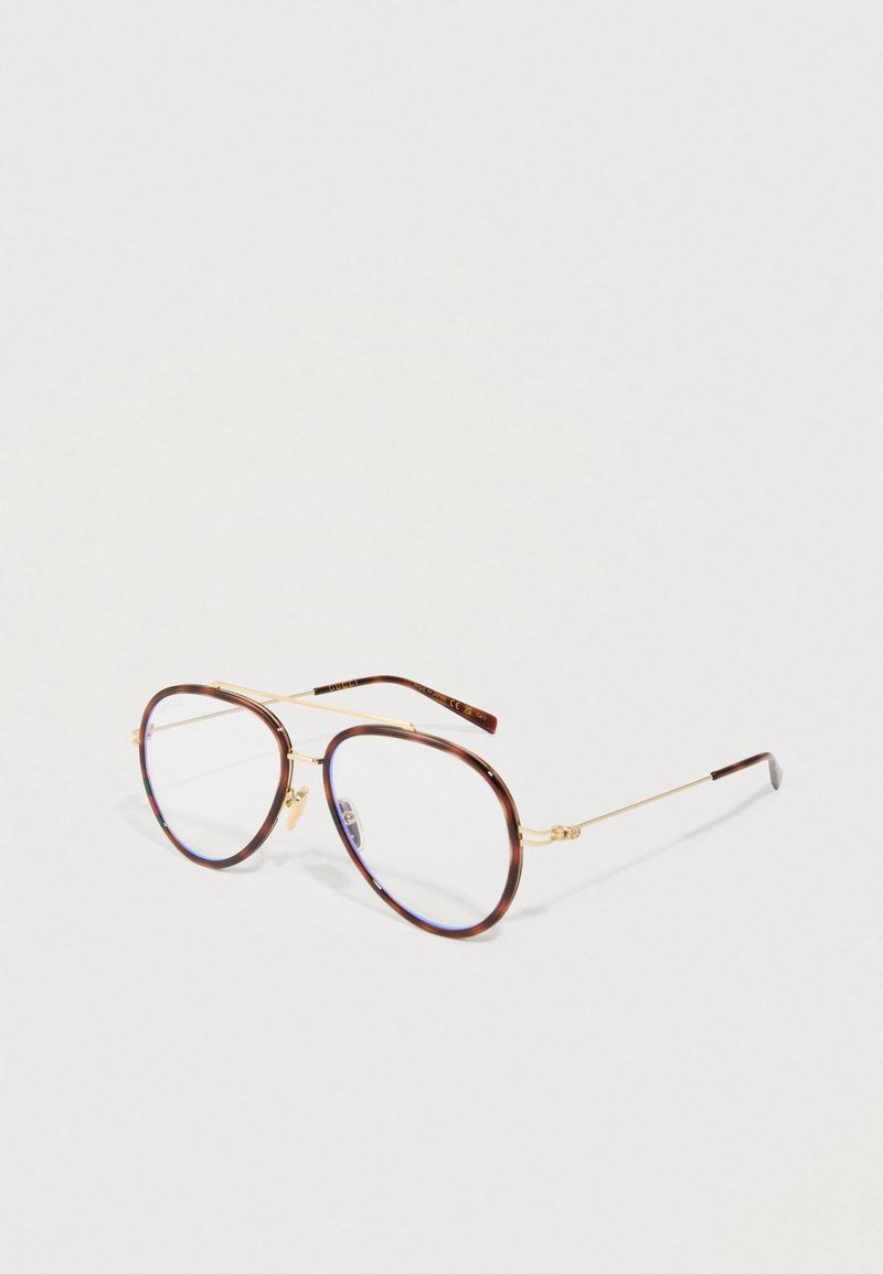 Okrogle očala s tankimi zlatimi metalnimi ročaji in rjavimi ohišji iz želvje školjke, prikazana na enobarvni beli podlagi.