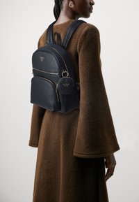 Zaino in pelle nera con due tasche frontali con zip, dettagli con logo e spallacci regolabili. Lo zaino presenta una piccola borsa con zip.