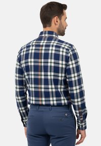 Camisa a cuadros en azul marino y blanco con acentos en verde y beige, que presenta un cuello clásico y puños con botones, hecha de una tela suave y texturizada.