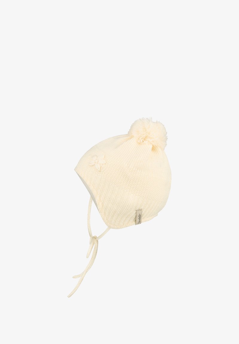 Cremefarbener, gestrickter Babyhut mit Ohrenklappen, Bindebändern, Pompon auf der Oberseite und kleinen Blütendetails an der Seite.