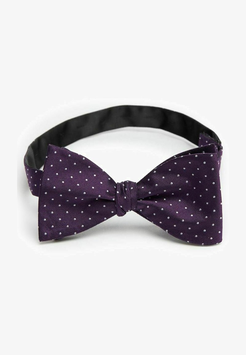 Lila fluga med vita prickar, tillverkad av strukturerad tyg. Justerbar rem med en slät svart innerfoder. Klassisk form.