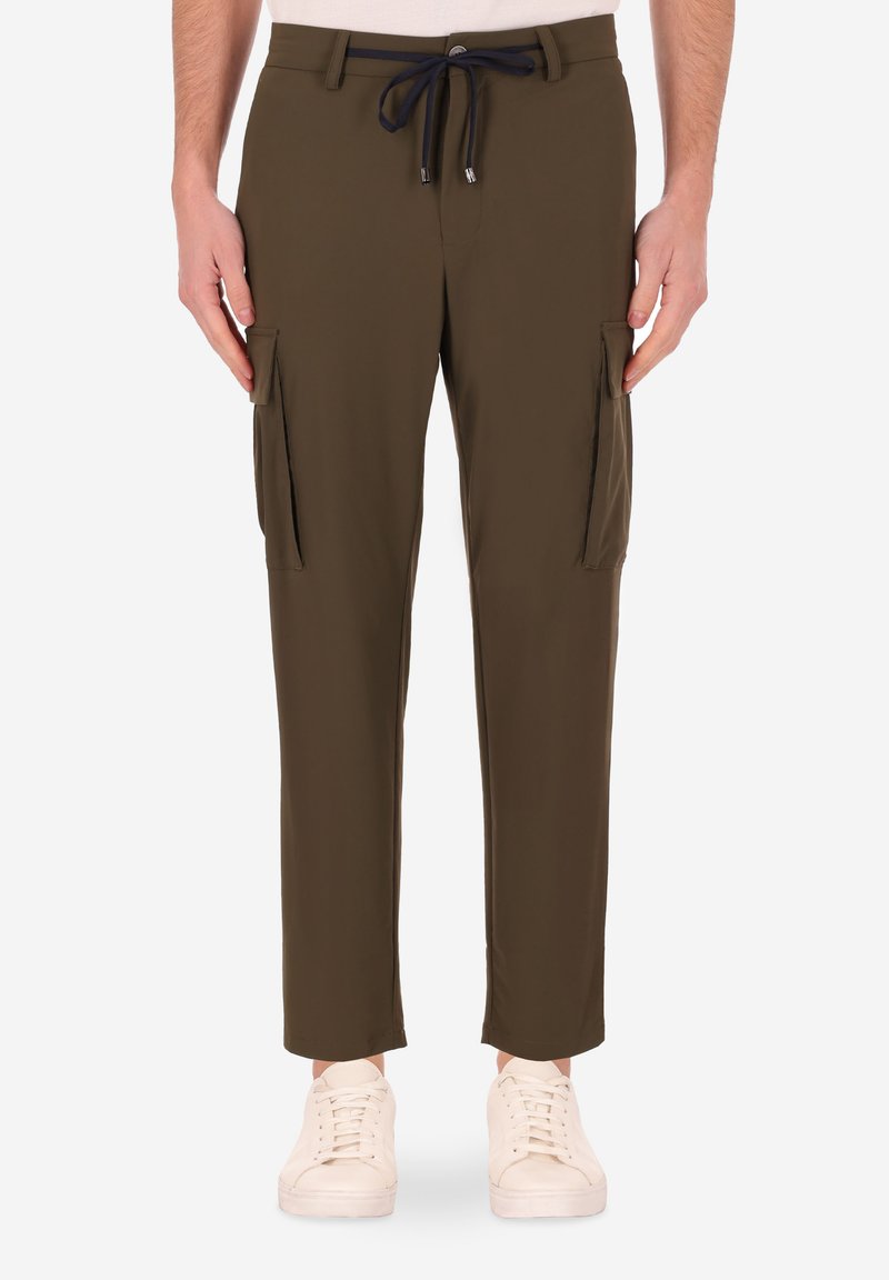 Pantaloni cargo verde oliva con vita regolabile, vestibilità slim, due tasche laterali e tessuto testurizzato. Le scarpe sono sneakers bianche.