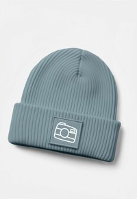 Ribbed light blue beanie hat with a folded cuff featuring a white camera graphic on a rectangular patch. Soft texture, flexible fit.