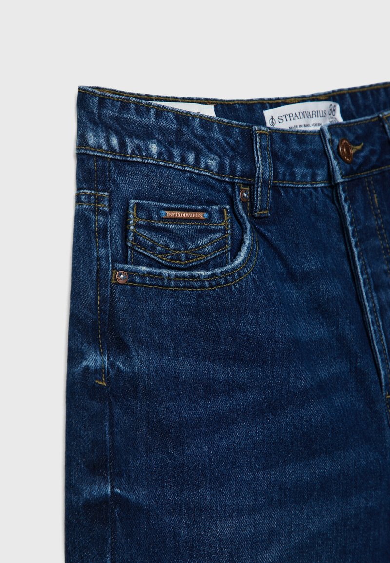 Dunkelblaue Denim-Jeans mit einer strukturierten Oberfläche, ausgestattet mit einer kleinen Vorder- tasche, einem Etikett und kontrastierenden Nähten. Klassisches Fünf-Taschen-Design.