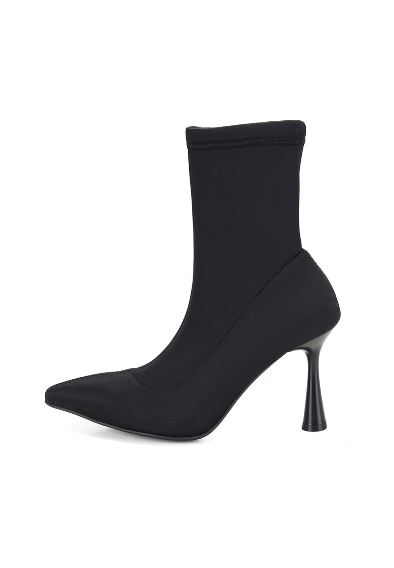 Bottine noire à bout pointu, en tissu extensible, avec un talon haut et fin. Présente une texture lisse et sans métal apparent ni embellissements.