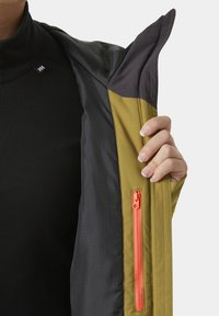 Outdoor-Jacke mit schwarzem Innenfutter und gelbem Außenmaterial; verfügt über einen kontrastierenden orangefarbenen Reißverschluss und eine strukturierte Kapuze.