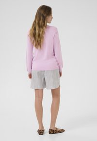 Light pink pullover sweater, long sleeves, ribbed hem, paired with striped shorts in white and gray. Brown leopard print flat shoes.
