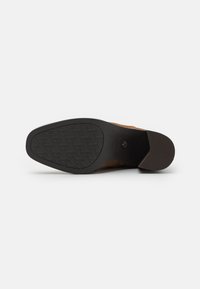 Talpa de pantof din suede maro, cu un底 din cauciuc negru texturat, având un model de profil și un toc ușor. Fără logo-uri sau accente vizibile.