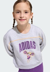 Szara bluza z fioletowym napisem "ADIDAS", żółtym przeszyciem oraz grafiką postaci z pomponami. Połączona z fioletowymi legginsami.
