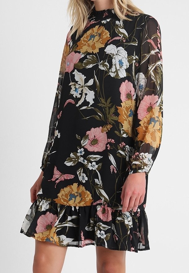 Robe noire à manches longues avec un grand imprimé floral rose, blanc et jaune, avec un col montant et un ourlet volanté au-dessus du genou.