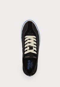 Black canvas sneaker with cream laces, contrasting blue sole, and stitching accents. Features a logo inside the shoe. Rounded toe design.