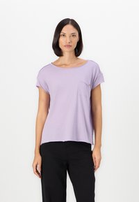 Lichtpaarse korte mouwen t-shirt met een ronde halslijn en een zak aan de voorkant. Zachte stof met een relaxte pasvorm, gecombineerd met zwarte broek.