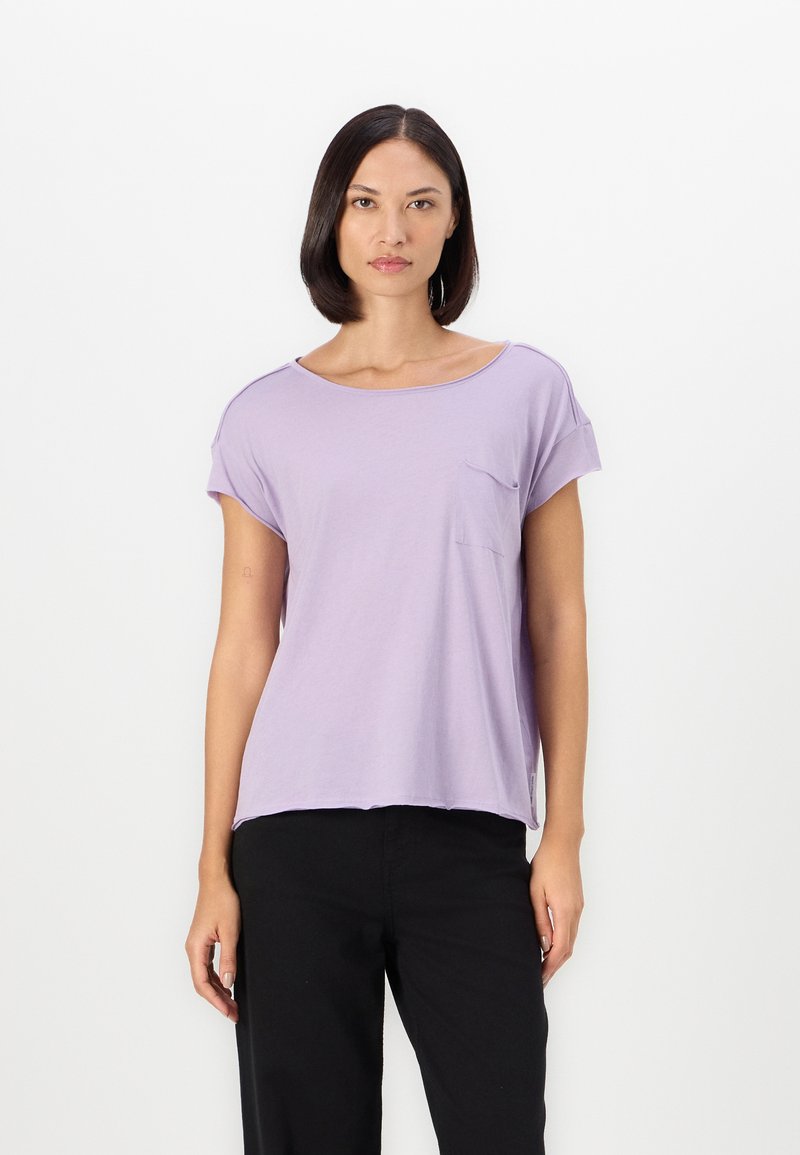 Lichtpaarse korte mouwen t-shirt met een ronde halslijn en een zak aan de voorkant. Zachte stof met een relaxte pasvorm, gecombineerd met zwarte broek.