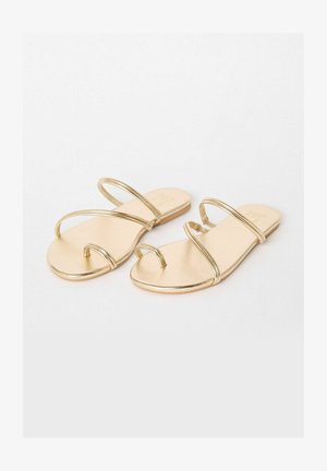Zlaté metalické ploché sandály s dvěma štíhlými zkříženými popruhy, otevřenou špičkou a hladkou plochou podrážkou. Jednoduchý a elegantní design.