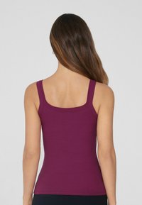 Figurbetontes, geripptes Tanktop in dunklem Lila mit breiten Schulterträgern und einem abgerundeten Rückenausschnitt. Weicher Stoff und dehnbarem Material.