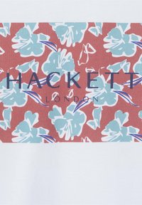 T-shirt bianco con motivo floreale in azzurro chiaro e rosso, con il testo "HACKETT" in evidenza in navy.