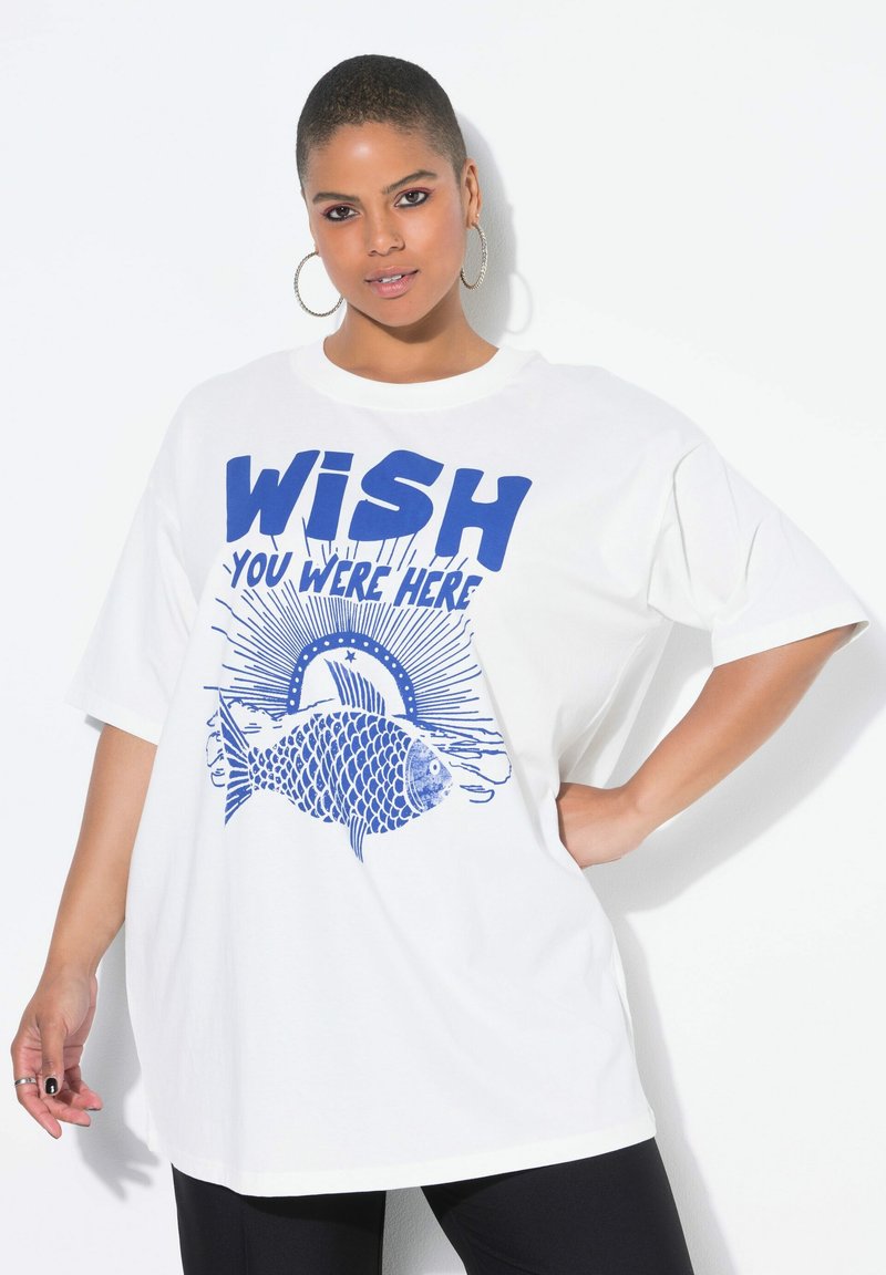 Witte oversized t-shirt met een blauwe grafische afbeelding met de tekst "WISH YOU WERE HERE" en een visillustratie. Korte mouwen, ronde hals.