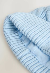 Un bonnet tricoté bleu clair avec un design côtelé, présentant un tissu doux et texturé et un rebord replié. L'intérieur montre une doublure lisse.