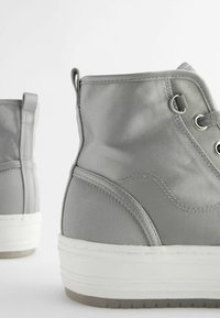 Gray high-top sneakers made of smooth fabric, featuring metal eyelets, a stitched design, and a white rubber sole with textured tread.