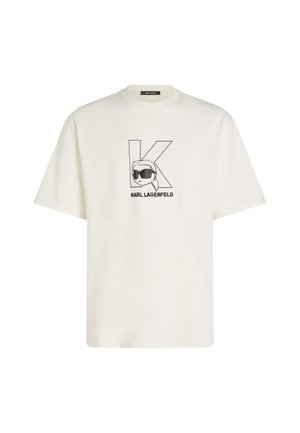Bijela pamučna majica s crnim grafičkim otiskom stiliziranog lica sa sunčanim naočalama i velikim "K" na prednjem dijelu. Kratki rukavi, opušteni kroj.