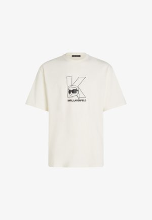 Valge puuvillane T-särk, mille esiküljel on must graafiline trükk stiliseeritud näost prillidega ja suure "K"-ga. Lühikesed varrukad, mugav lõige.
