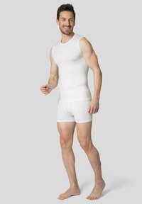 Débardeur blanc sans manches et boxers en tissu lisse, présentant un design ajusté avec des coutures minimales et une légère élasticité.