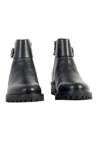 Botas de tobillo de cuero negro con punta redonda, suela de goma gruesa, detalle de hebilla en el costado y parte superior texturizada. Diseño limpio y minimalista.