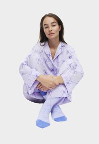 Hellblaues Pyjama-Set mit floralem Muster und langen Ärmeln. Hellblaue Socken mit dunkleren blauen Akzenten und Mustern. Weicher Stoff.