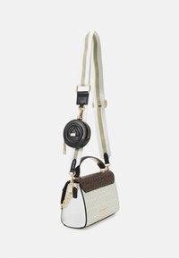 Sac structuré avec un motif géométrique crème et marron, des accents noirs, du matériel doré et une pochette ronde détachable. Sangle réglable incluse.
