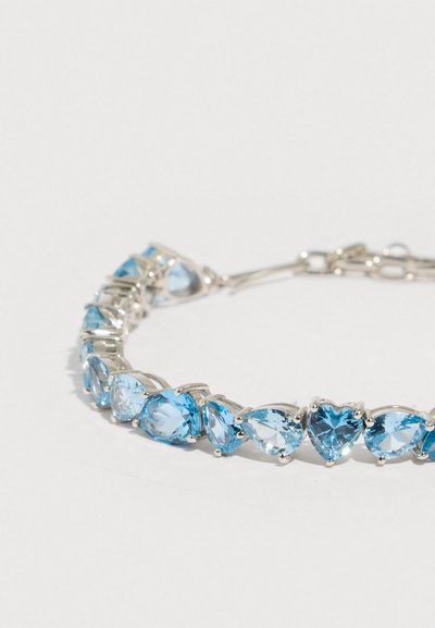 Pulseira de prata com pedras preciosas azul claro alternadas em forma de coração e lágrima, com acabamento polido e design de fecho seguro.