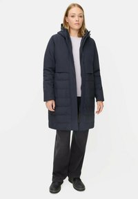 Mørkeblå puffjakke med hætte, med lynlås foran, to store forlommer og knælangt design for varme. Blød tekstur.