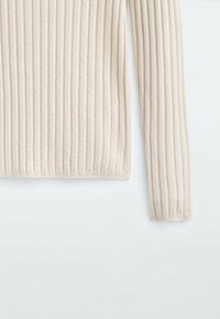 Pull à manches longues en tricot côtelé de couleur crème avec de fines rayures verticales sur un fond blanc uni.