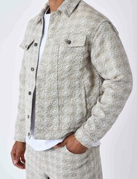 Lysgrå mønstret denimjakke med diamantmotiv, der har klaplommer på brystet, metalknapper og klassisk krave.