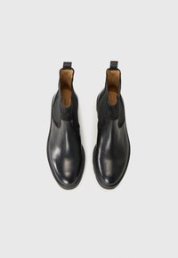 Bottines Chelsea en cuir noir avec panneaux élastiques sur les côtés et bout arrondi. Texture lisse et silhouette élancée avec doublure en cuir.