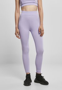 Lilla tights laget av elastisk stoff, høy midje, tettsittende design. Kombinert med svarte treningssko, minimale detaljer. Hvit bakgrunn.