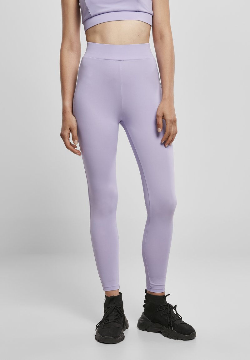 Lilla tights laget av elastisk stoff, høy midje, tettsittende design. Kombinert med svarte treningssko, minimale detaljer. Hvit bakgrunn.