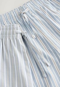 Shorts de pyjama rayés en bleu clair, gris et blanc. Matière douce, taille élastique avec cordon de serrage, et poches latérales.