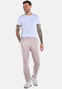 Helle rosa maßgeschneiderte Hose mit glatter Textur, featuring einen einzelnen Knopfverschluss und Seitentaschen, kombiniert mit einem weißen T-Shirt und Turnschuhen.