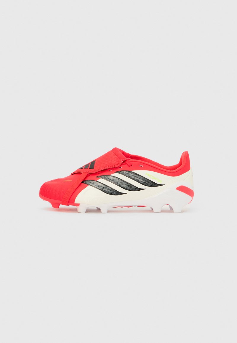 Chaussure de football Adidas Predator rouge et blanche avec des rayures noires et une semelle cloutée, conçue pour la performance et l'adhérence sur gazon.