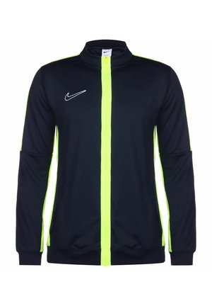 Giacca Nike di colore blu navy con zip giallo brillante. Presenta un colletto alto, maniche lunghe e un logo bianco sul lato sinistro. Tessuto liscio.