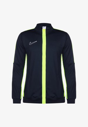 Nike jack in marineblauw met een felgele rits. Heeft een hoge kraag, lange mouwen en een wit logo aan de linkerkant. Soepele stof.